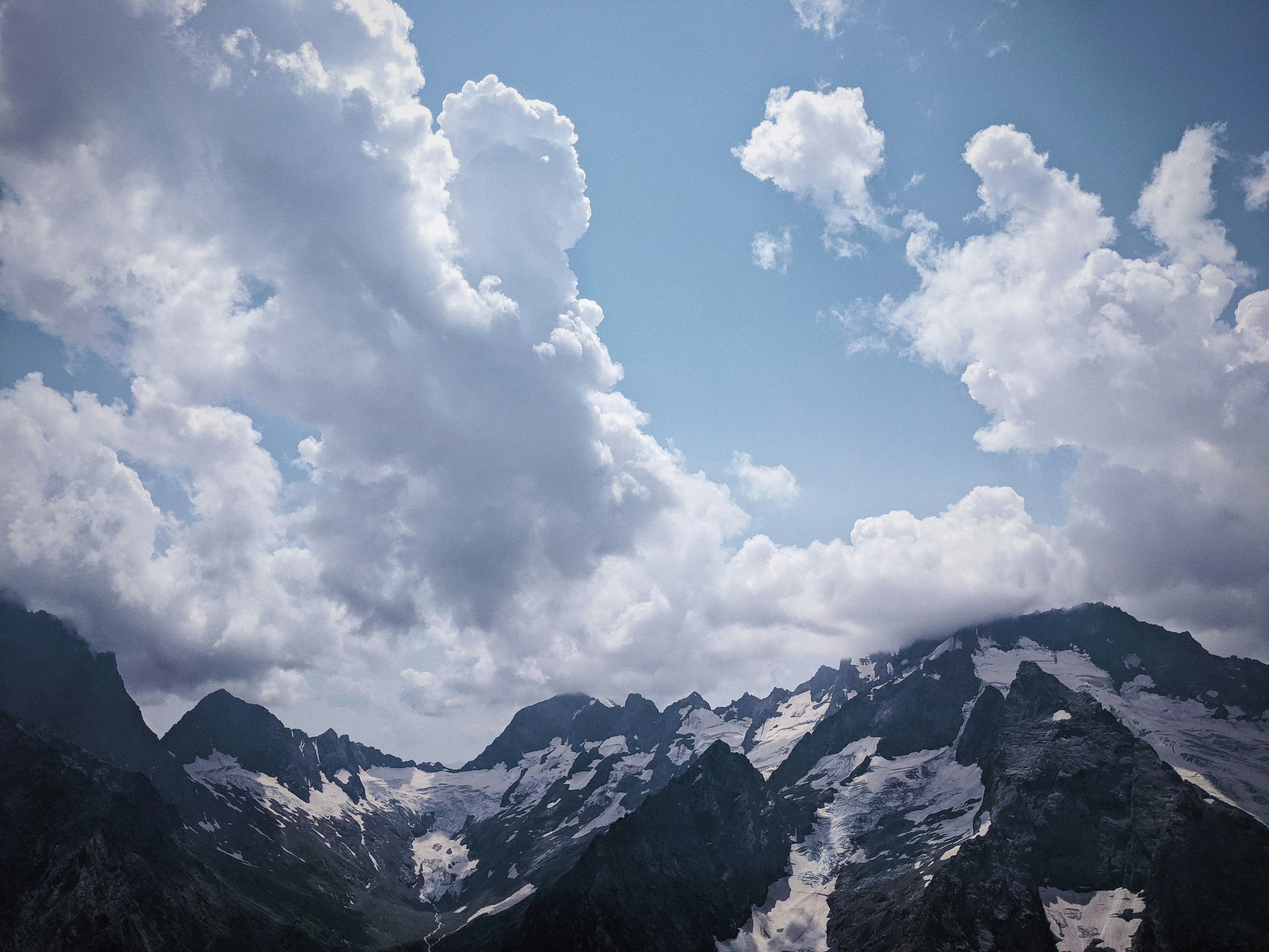 white clouds over snow covered mountains